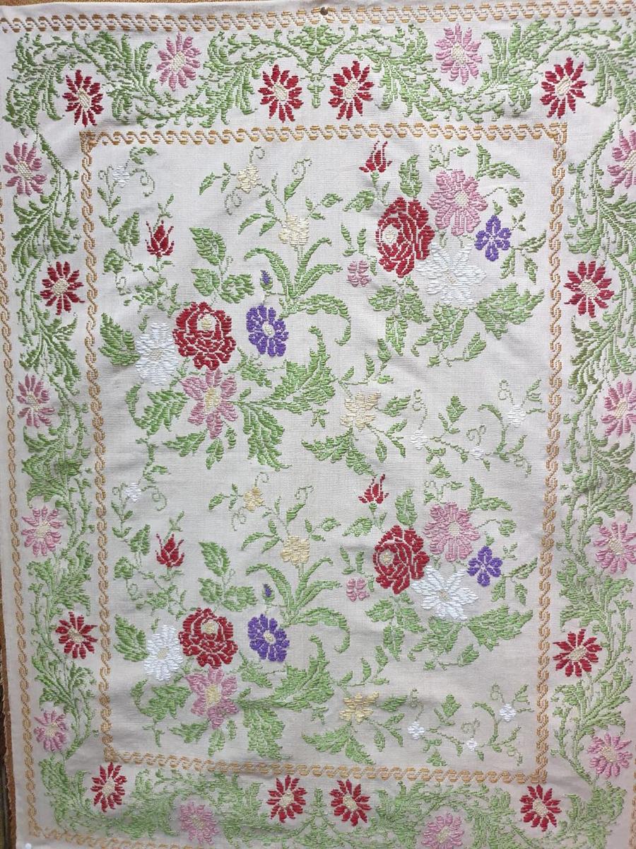 Copriletto chiaro tessuto a mano con rose rosse e rosa, fiori viola e tralci verdi dentro una bordura