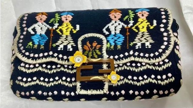 Patta della Baguette Fendi blu notte tessuta a mano: due coppie in festa, l'uomo in camicia bianca e la donna in giallo, tra bordure ondulate color avorio